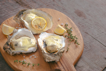 Tasty fresh oysters with sliced lemon on cutting board. Aphrodisiac food for increasing sexual desire