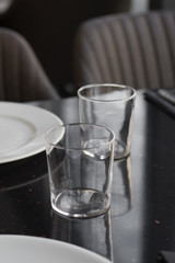 White plates, glasses and utensils on black table, elegant tableware