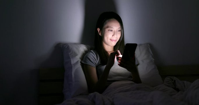 Woman use of smart phone on bed at home