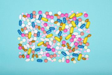 Assortment of various colourful pills on pastel coloured background. Medication and prescription pills flat lay background.