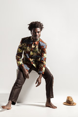 Afro man in national kongo national costume sit on cube.