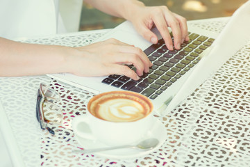 Women work, drink coffee, and use white notebooks on the table.