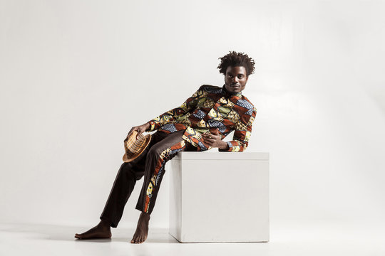 Barefooted african man uncomfortble sit on cube