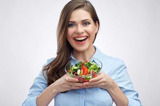 Smiling woman holding glass bowl with vegetable salad.