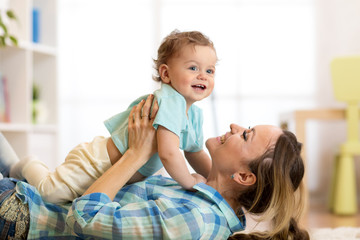 Side view portrait of a happy mother lying on the floor with her baby son at home