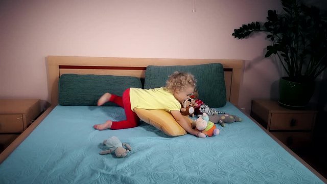 mischievous child throwing toys on bed in bedroom.