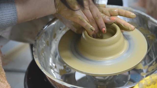 The teenager works with clay on a potter's wheel. Creative hobby work with clay.
