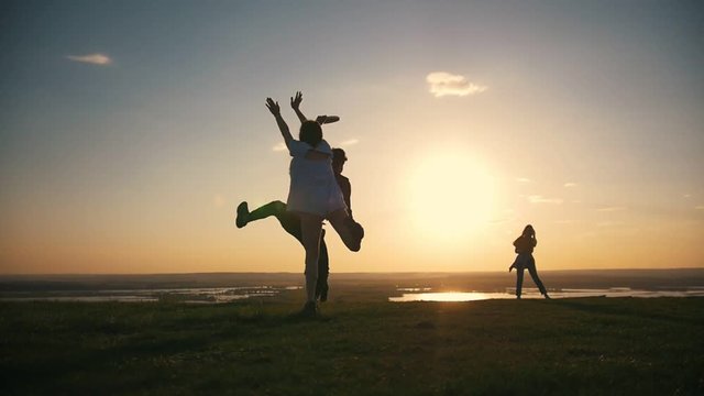 Happy young friends throwing frisbee on the hill at sunset