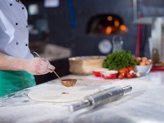 Chef smearing pizza dough with ketchup