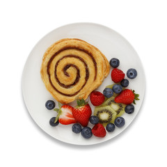 Cinnamon Swirl and fruit on a white plate, with a drop shadow, shot from above.