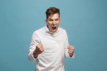 The young emotional angry man screaming on studio background