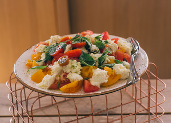 Green salad with vegetables on the metalic net and wooden table