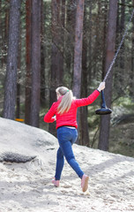 Happy blonde teenager girl jumping with bungee in park