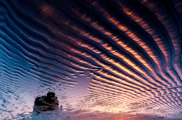 Black wavy sand pattern lit by sunlight.
