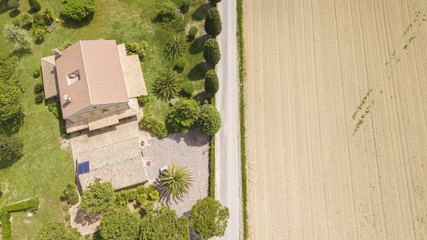 Perpendicular aerial view of a road passing near a villa and cuts through the fields of...