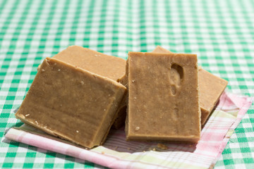 Pacoca is a candy with peanuts from Brazil. Sweet food of Festa Junina, a typical brazilian party. Snack on wicker basket and green background.