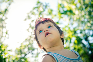 Naklejka premium Cute little girl is sitting in a meadow in the spring. Little girl outdoors in summer. Day of childhood. Children's Day June 1. little girl in a cap 