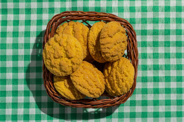 Delicious yellow cookie of corn on basket and green plaid table. Sweet food of Festa Junina, a typical brazilian party.