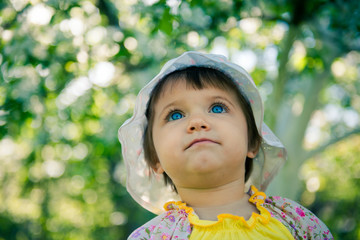 Cute little girl is sitting in a meadow in the spring. Little girl outdoors in summer. Day of childhood. Children's Day June 1. little girl in a cap
