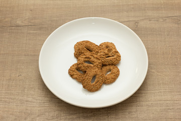 Cookies with a hole, sweet temptation. Dessert on white dish and wooden table.