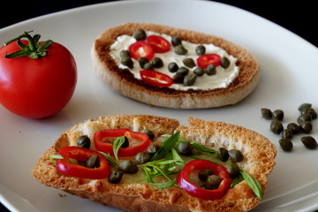 Snacks with fresh green thyme, peppers, tomato, cheese, capers and toasted bread.