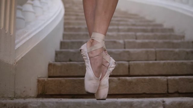Close up of a woman's feet in beige pointe. Young, beautiful ballerina demonstrating ballet movements. Black tutu. Upward footage