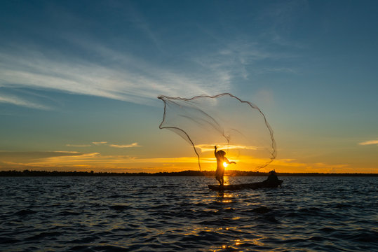 Un-identified silhouette fisher man on boat fishing by throwing fishing net