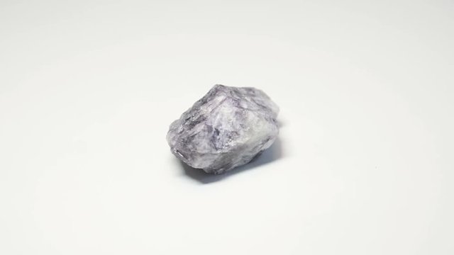 Macro shot of fluorite mineral isolated over white background and spinning around
