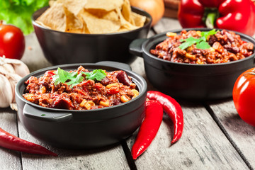 Bowls of hot chili con carne with ground beef, beans, tomatoes and corn