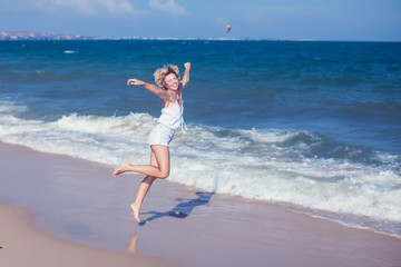 Happy beautiful free woman running on the beach jumping playful having fun