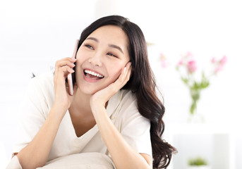 happy woman sitting on couch and talking on the phone