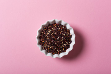 Top view of black Quinoa in white bowls on pink background. Flat lay with copy space. Healthy gluten free food concept.