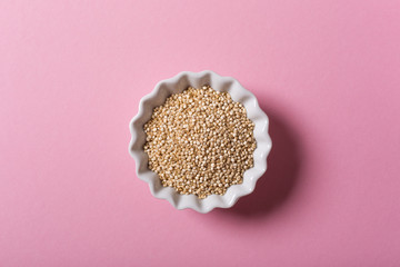 Top view of white Quinoa in white bowls on pink background. Flat lay with copy space. Healthy...