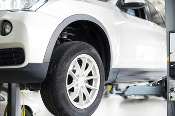 Car on a wheel alignment lift in auto service. Diagnosis of the chassis of the car raised at the elevator.