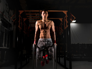 Fototapeta na wymiar A young sportsman in the gym. Do exercises on the uneven bars. Training in the gym.