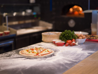 chef putting fresh vegetables on pizza dough