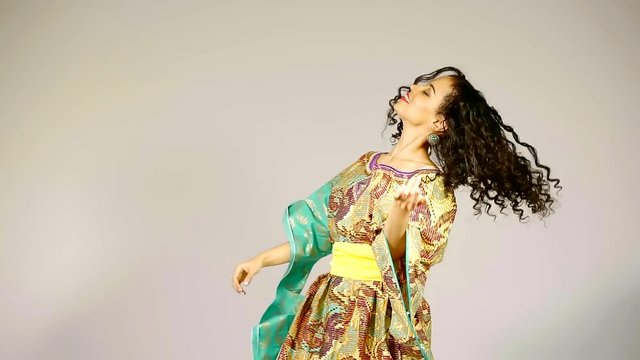 cute and young woman dressed in bright dress dancing and jumping in studio