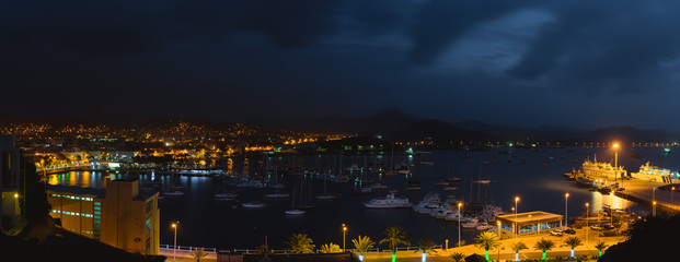 Fototapeta na wymiar Mindelo in dusk light. Port town with many boats in the bay on the Cape Verde in the northern part of the island Sao Vicente. Long exposure panoramic shot of the bay
