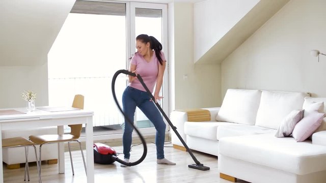 household, housework and cleaning concept - happy woman or housewife with vacuum cleaner dancing at home