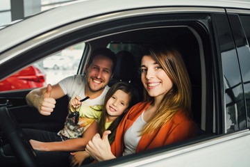 Family buying a new car in the car dealership saloon.