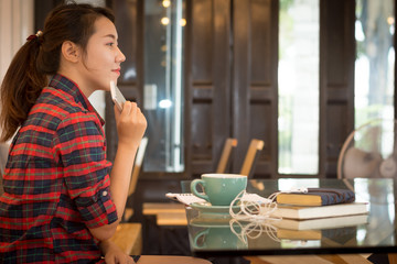 Young woman holding mobile phone while sitting in coffee shop.