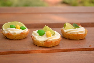 Sweet creamy cakes with lime on wooden table decoration
