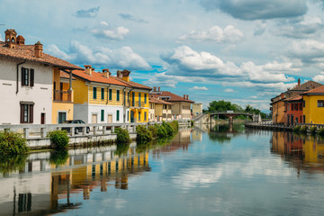 Fototapeta na wymiar Naviglio Grande canal waterway passes near the historic and colorful buildings of Gaggiano Italy