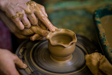 Creating jar or vase of clay close-up. Master crock. Man hands making clay jug macro. sculptor in workshop jug out of earthenware closeup. Twisted potter's wheel