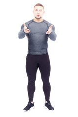 Portrait of handsome well-muscled gym instructor in sports tights and rashguard posing on white background