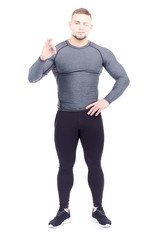 Portrait of handsome well-muscled gym instructor in sports tights and rashguard posing on white background