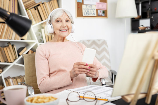 Native speakers speech. Gay mature woman listening to audio and staring at camera