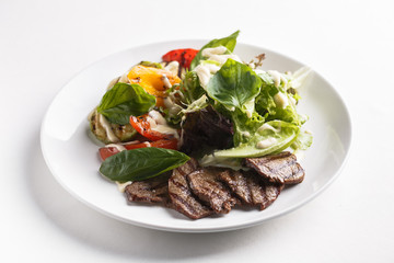 Warm salad with beef and vegetables. Served on a white plate