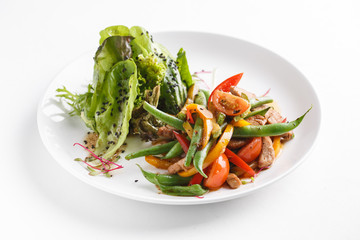 Warm salad of pork with green beans. Served on a white plate