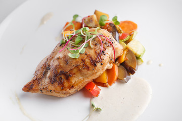 Grilled chicken breast with vegetables. Served on a white plate